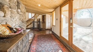 Ein Holzinnenraum mit einer Steinwand, einer Treppe und Blick ins Freie.