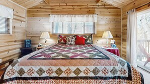 Een gezellig slaapkamer in een houten blokhut met een groot bed, twee bedlampen en een raam met luiken.