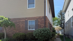 A two-story residential building with a brick facade, a visible window with shutters, and a small front yard with grass and a tree. - Comfortable Modern Stay Quiet 1BR Retreat Near Dayton, Eaton, Miami U& Richmond (Eaton)