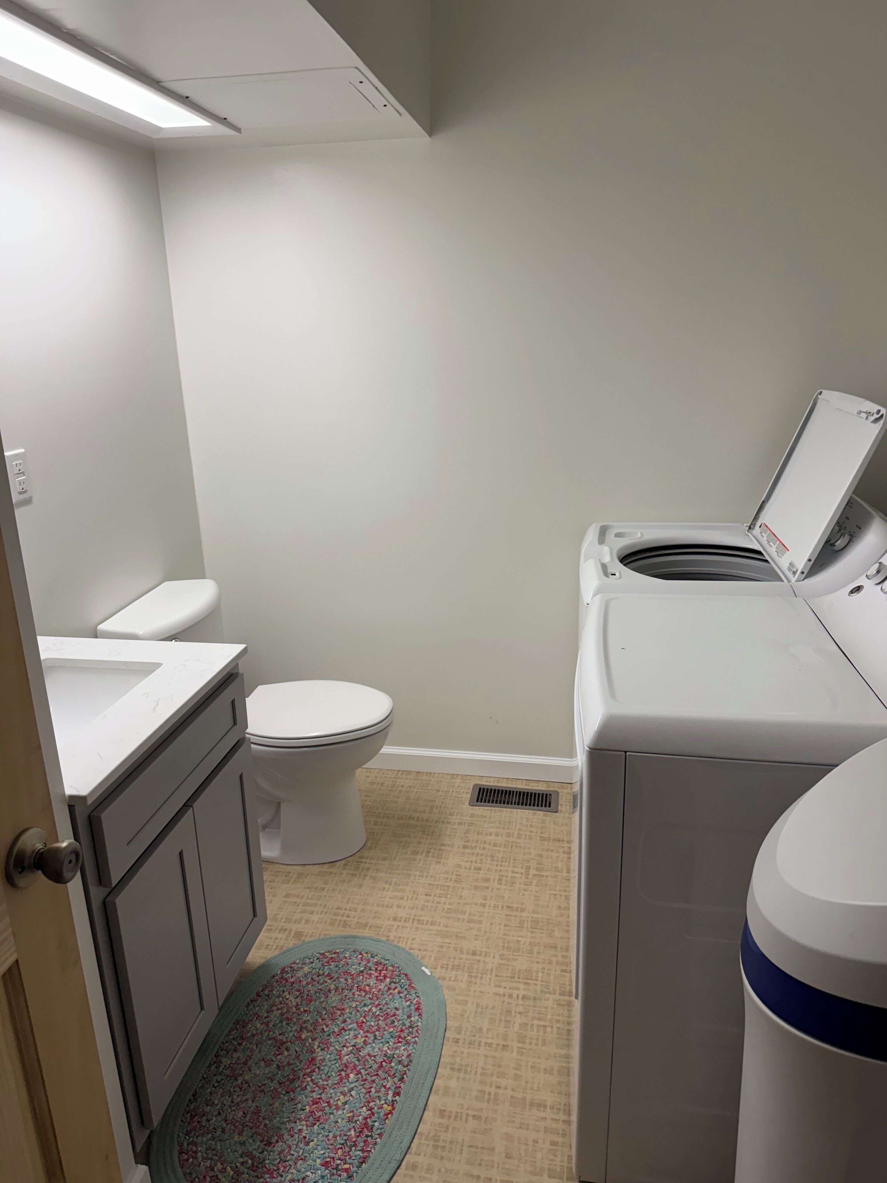 A compact bathroom with a toilet, a washing machine, and a sink.