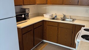 A kitchen with wooden cabinets, a white refrigerator, a microwave, a sink, and a stove. - Comfortable Modern Stay Quiet 1BR Retreat Near Dayton, Eaton, Miami U& Richmond (Eaton)