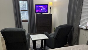 A bedroom with a bed, two armchairs, a small table, a TV on a dresser, and a lamp. - Comfortable Modern Stay Quiet 1BR Retreat Near Dayton, Eaton, Miami U& Richmond (Eaton)