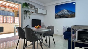 Sala de estar moderna com área de jantar, televisão montada, pintura de uma montanha e varanda com vista.