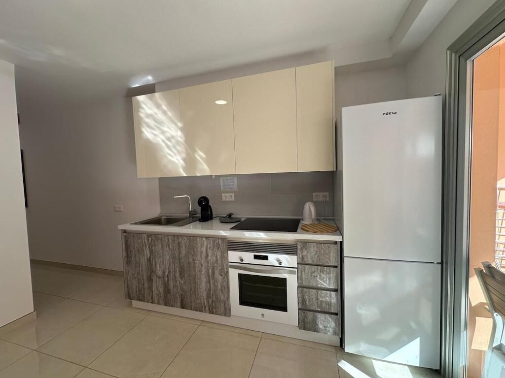 A modern kitchen with a built-in oven, a refrigerator, and a sink.
