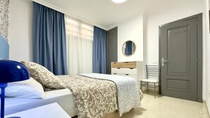 Quarto com cama, mesa de cabeceira, cadeira e porta.