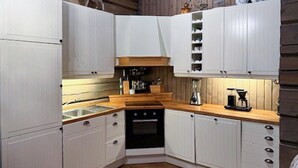 Une cuisine compacte avec des meubles blancs, un plan de travail en bois et un four encastré.