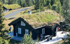 Une cabane avec un toit de chaume, une terrasse en bois et un banc.