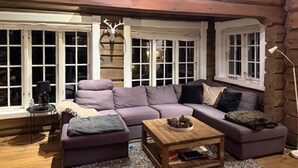 Un salon chaleureux avec un canapé d’angle, une table basse et une cheminée.