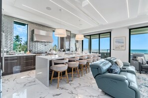 A modern kitchen with a large island, bar stools, and a view of the ocean. - Luxury Gulf-Front Sanctuary | Private Pool, Spa & Walk to Downtown (Fort Myers Beach)
