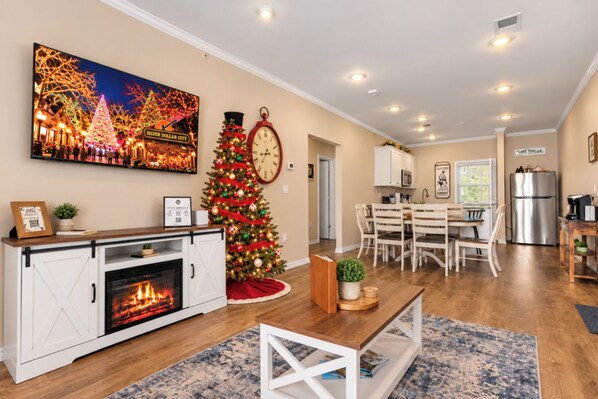A living room with a fireplace, a Christmas tree, and a dining area with a kitchen in the background. - Perfectly located for Branson fun, No step access, 2 pools and modern finishes. (Branson)