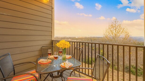 A balcony with a table set for two, chairs, and a view of the landscape. - Perfectly located for Branson fun, No step access, 2 pools and modern finishes. (Branson)