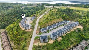 An aerial view of a residential area with a row of townhouses, a road, and surrounding greenery. - Perfectly located for Branson fun, No step access, 2 pools and modern finishes. (Branson)