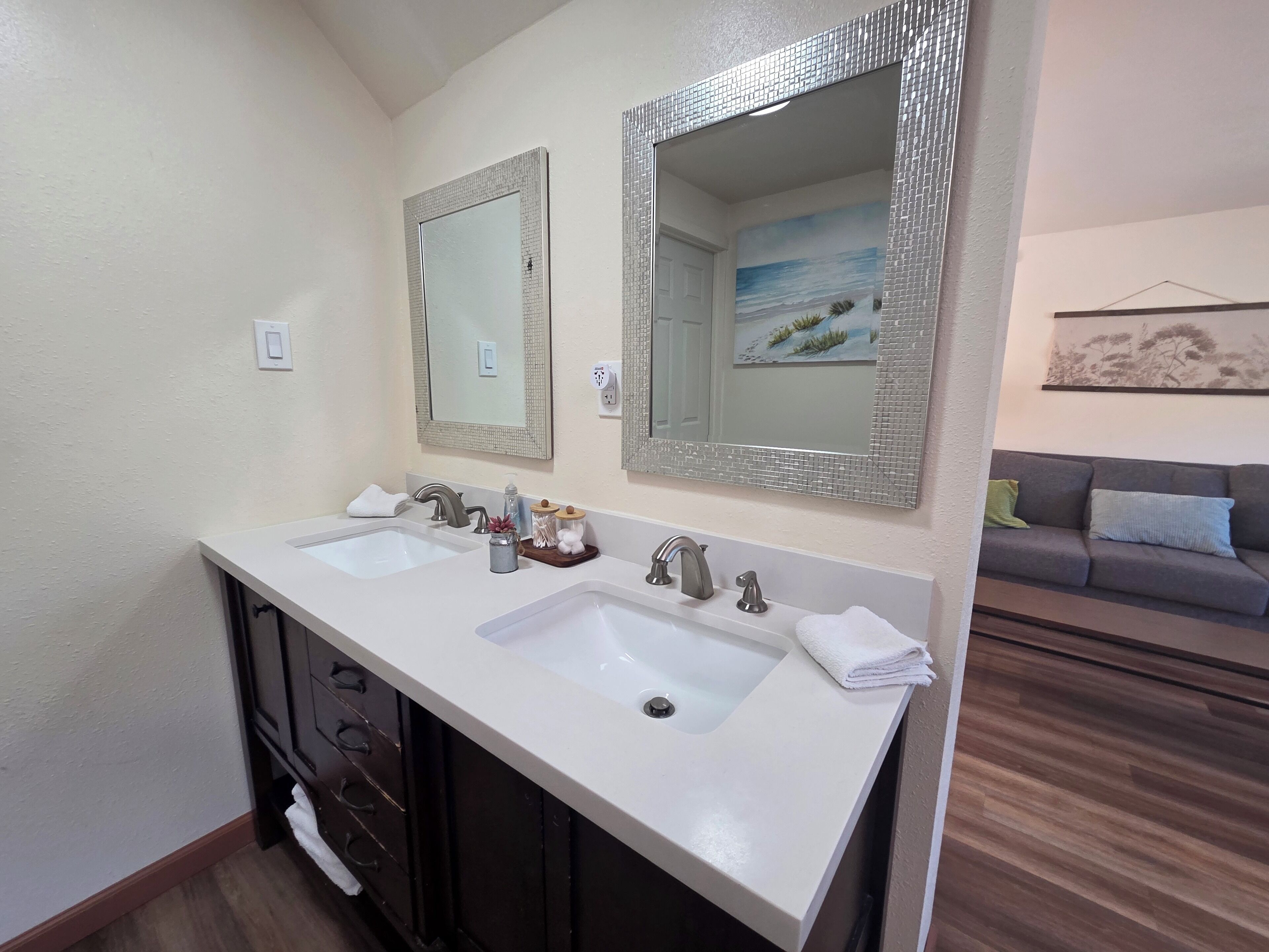 A bathroom with two sinks, dark wooden cabinets, and a mirror with a mosaic frame.