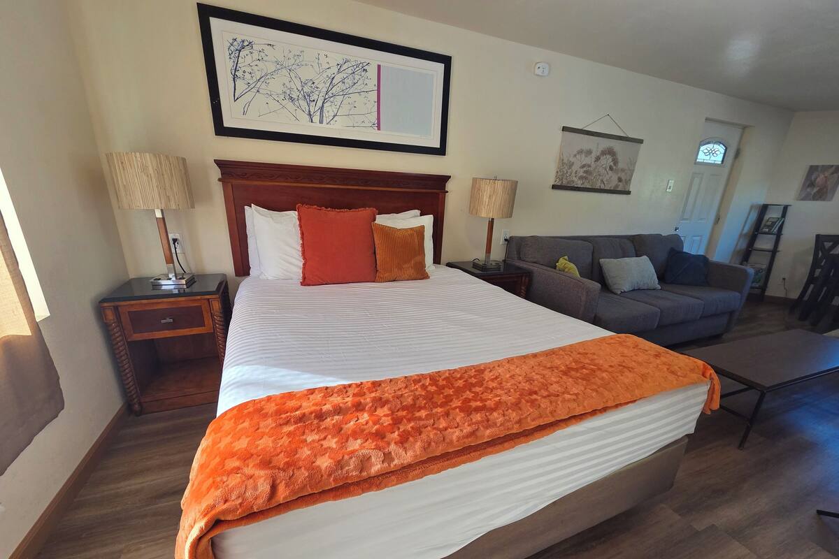 A hotel room with a large bed, a sofa, and a desk.