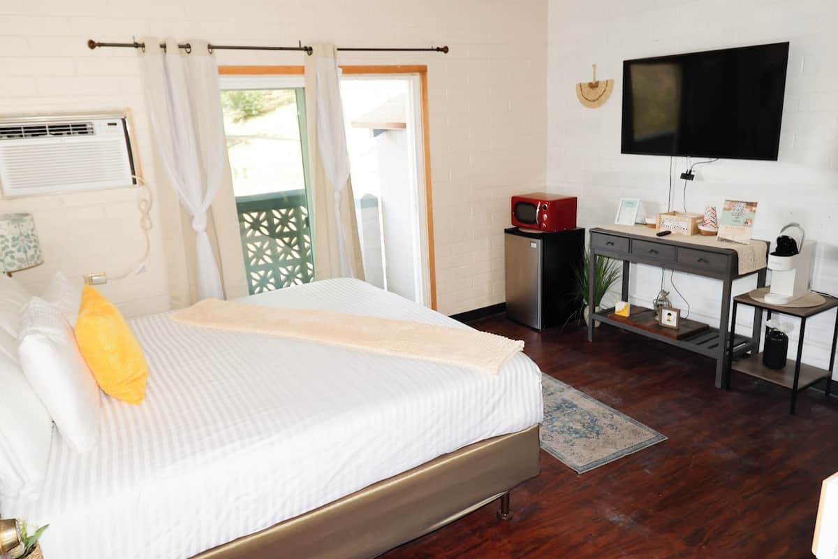 A hotel room with a bed, a desk, a television, and a window with curtains.