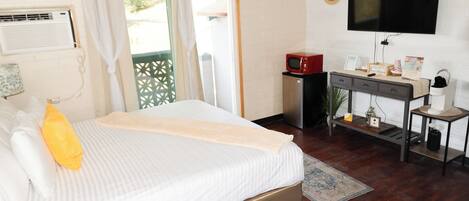 Une chambre d’hôtel avec un lit, un bureau, une télévision et une fenêtre avec des rideaux.