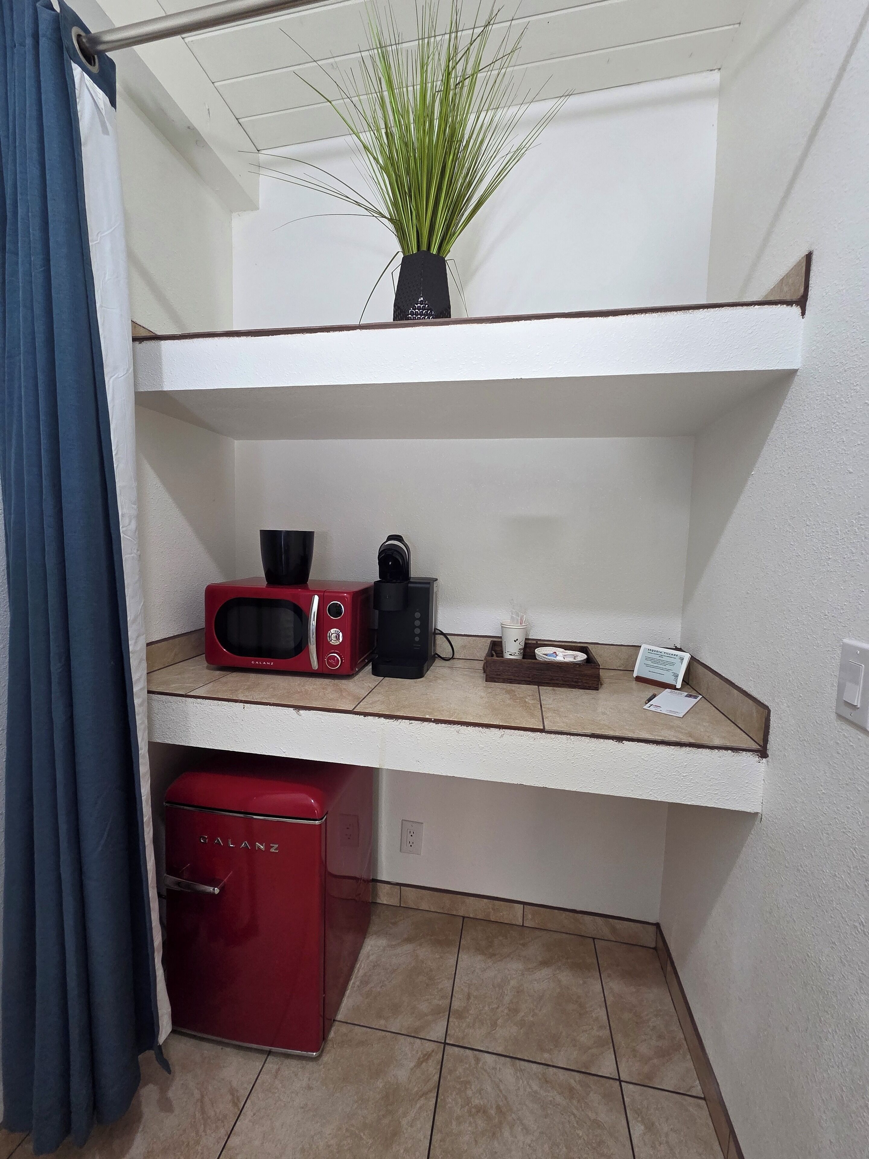 A kitchenette with a microwave, coffee maker, and a red mini-fridge.