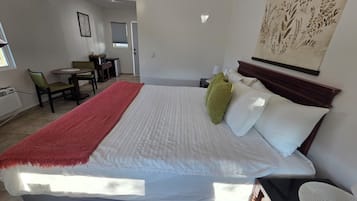 Habitación de hotel con cama, escritorio y silla. Se observa una ventana y una puerta en la habitación.
