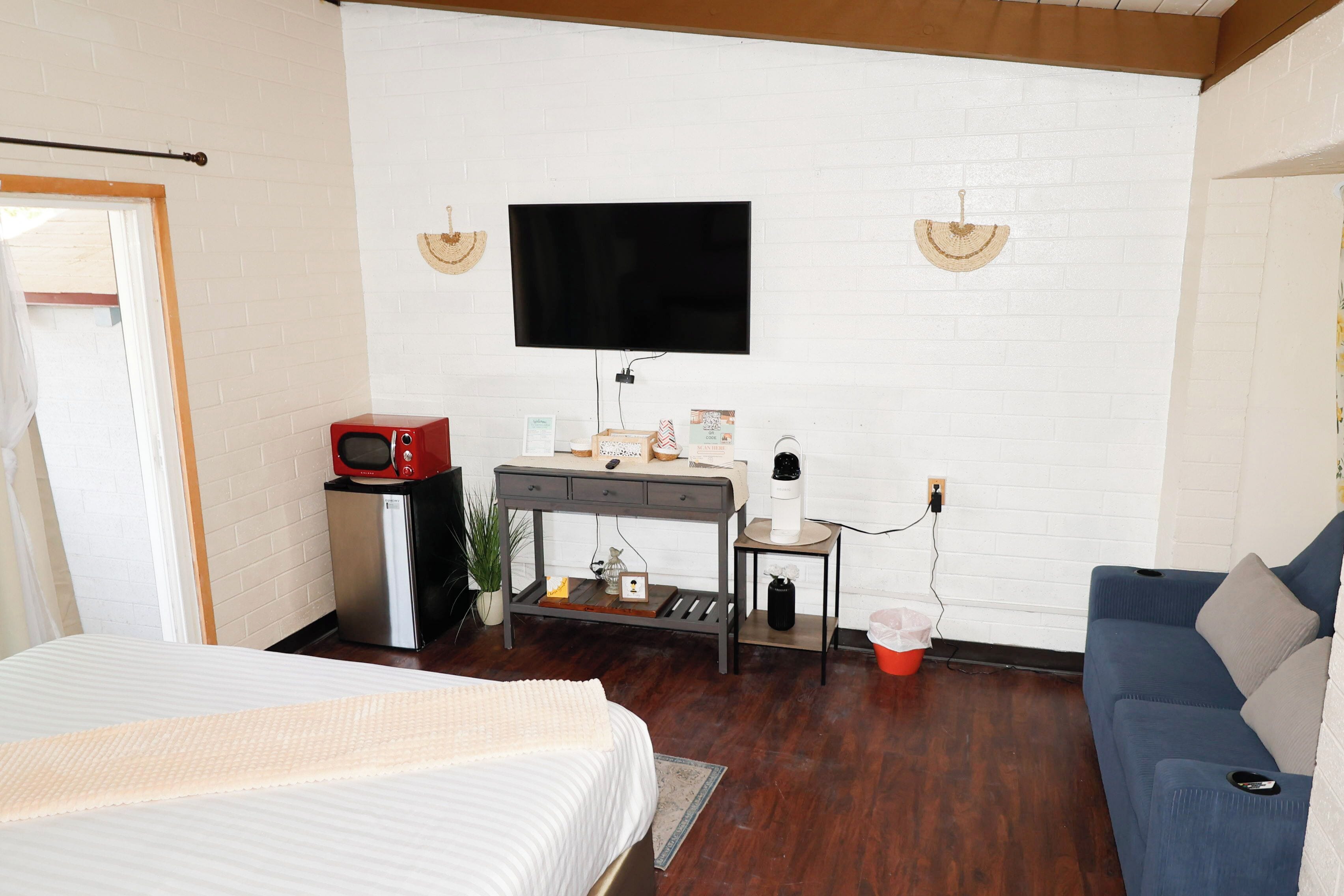 A bedroom with a bed, a desk, a TV, and a blue sofa.