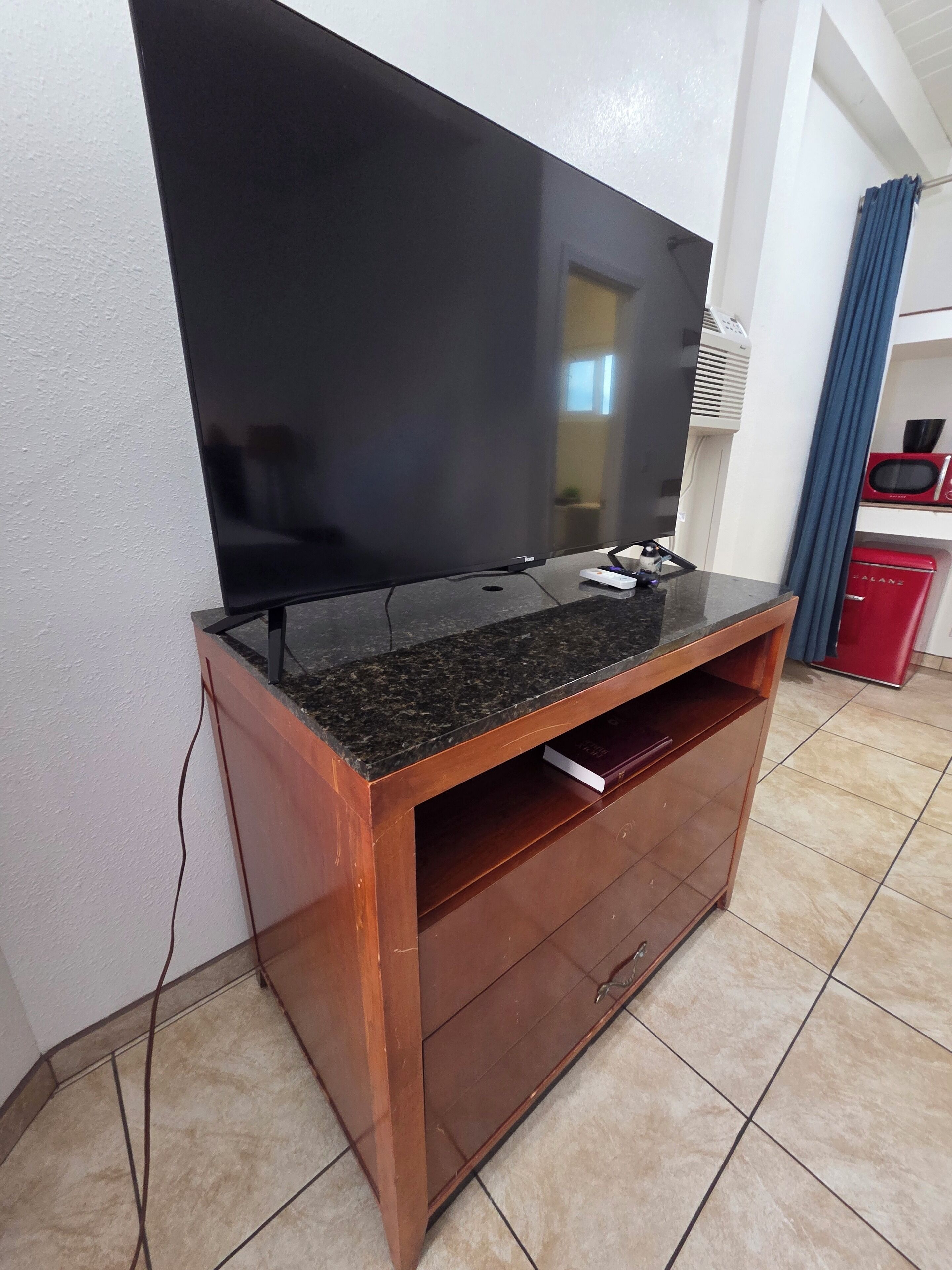 A flat-screen TV mounted on a wooden entertainment unit with a marble top.
