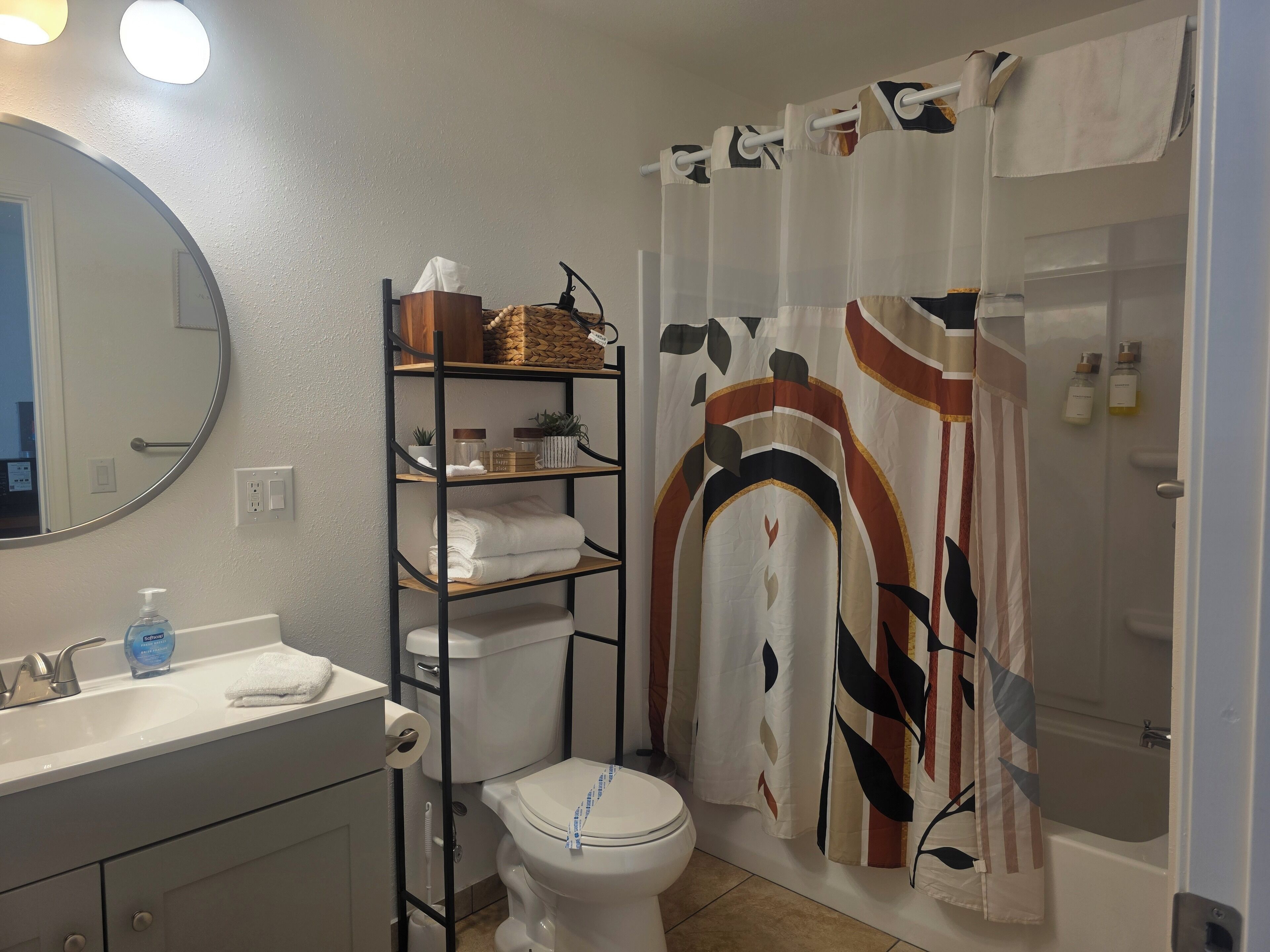 A bathroom with a toilet, sink, and shelves with toiletries.