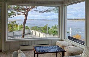 A room with a large window overlooking a body of water, a wooden table, and a cushioned bench. - 2 bedroom beautiful home in Gressvik (Gressvik)