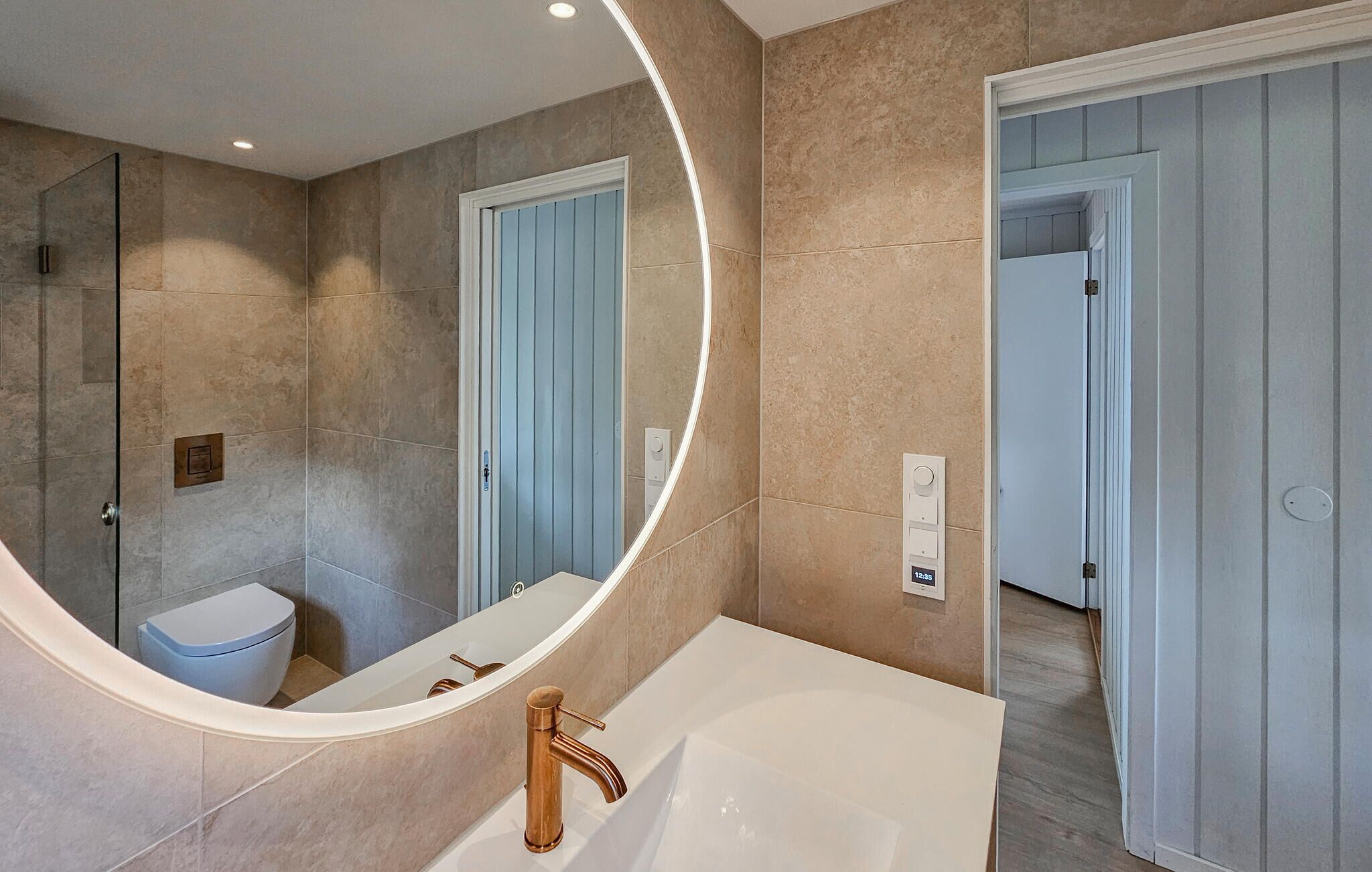 A modern bathroom with a large mirror, a bathtub, and a toilet.