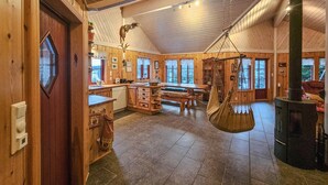 A rustic wooden interior with a kitchen, dining area, and a hanging hammock. - Gorgeous home in Steinsholt with harbor view (Steinsholt)