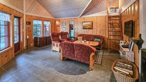 A cozy cabin interior with wooden walls, a stone-tiled floor, a dining table with chairs, a fireplace, and a bookshelf. - Gorgeous home in Steinsholt with harbor view (Steinsholt)