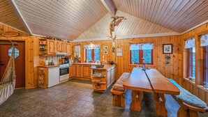 A cozy cabin with wooden interiors, a kitchen with a stove, and a dining area with benches. - Gorgeous home in Steinsholt with harbor view (Steinsholt)