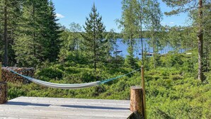 A hammock on a wooden deck overlooking a lake with trees and boats. - Gorgeous home in Steinsholt with harbor view (Steinsholt)