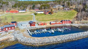 An aerial view of a coastal village with a marina, red buildings, and a rocky shoreline.