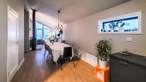 A dining area with a table set for four, a potted plant, and a view of the city through a window. - Stunning apartment in Tromsø with WiFi (Tromsø)