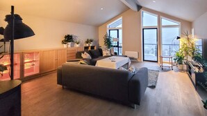 A modern living room with a sofa, a coffee table, and a dining table. There are potted plants and a cabinet with glass doors. - Stunning apartment in Tromsø with WiFi (Tromsø)