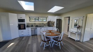 Une cuisine moderne avec des meubles blancs, un îlot central doté de sièges, des fenêtres de toit et une vue par la fenêtre.