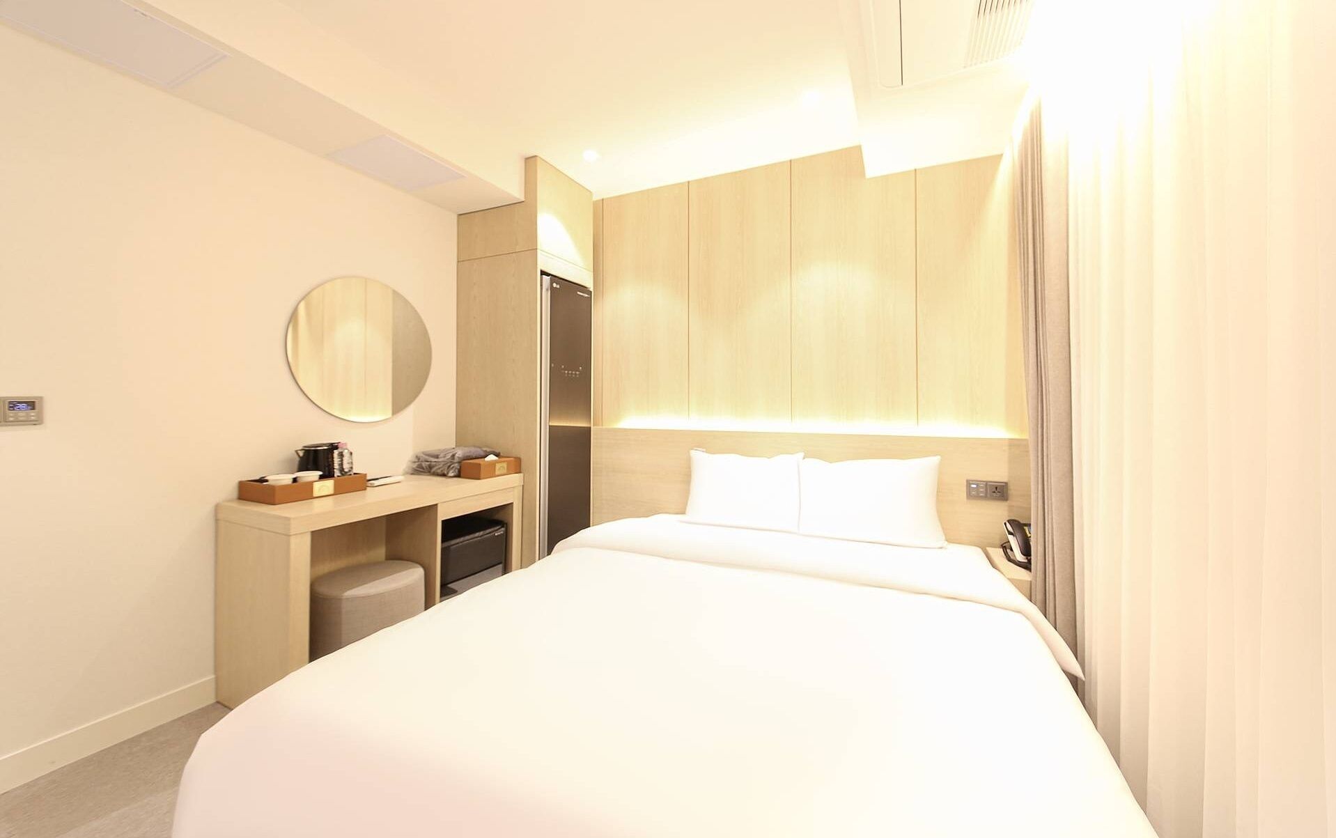 Habitació d'hotel amb un llit gran, una taula de nit amb mirall i una petita zona de seients.