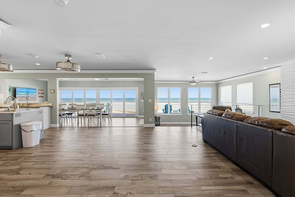 A spacious living area with a large window overlooking the ocean, a kitchen with a view, and a seating area with a view.