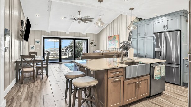 Una cucina moderna con una grande isola, elettrodomestici in acciaio inox e una ventola a soffitto.