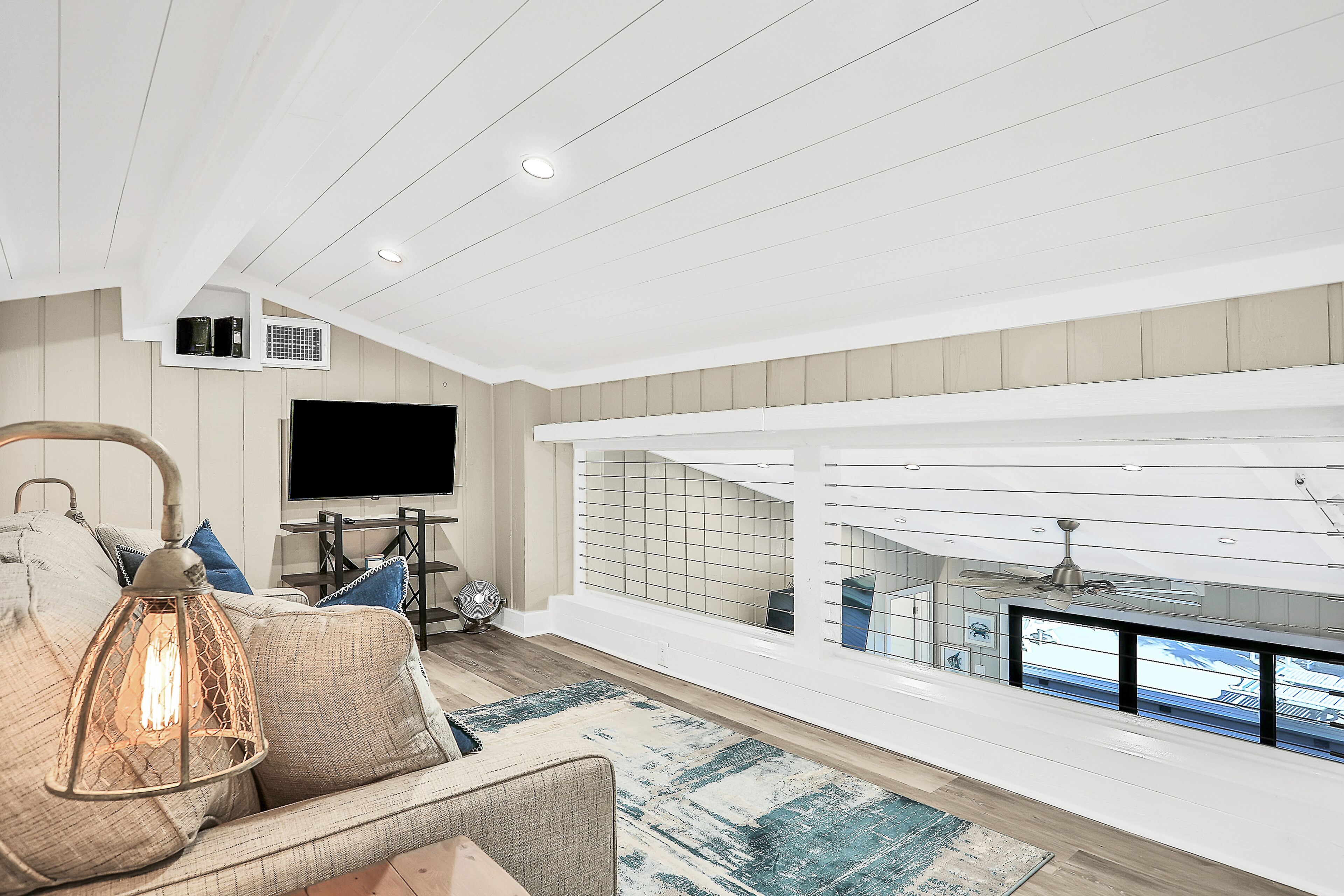 Una sala de estar moderna con un sofá, un televisor y vistas al exterior.