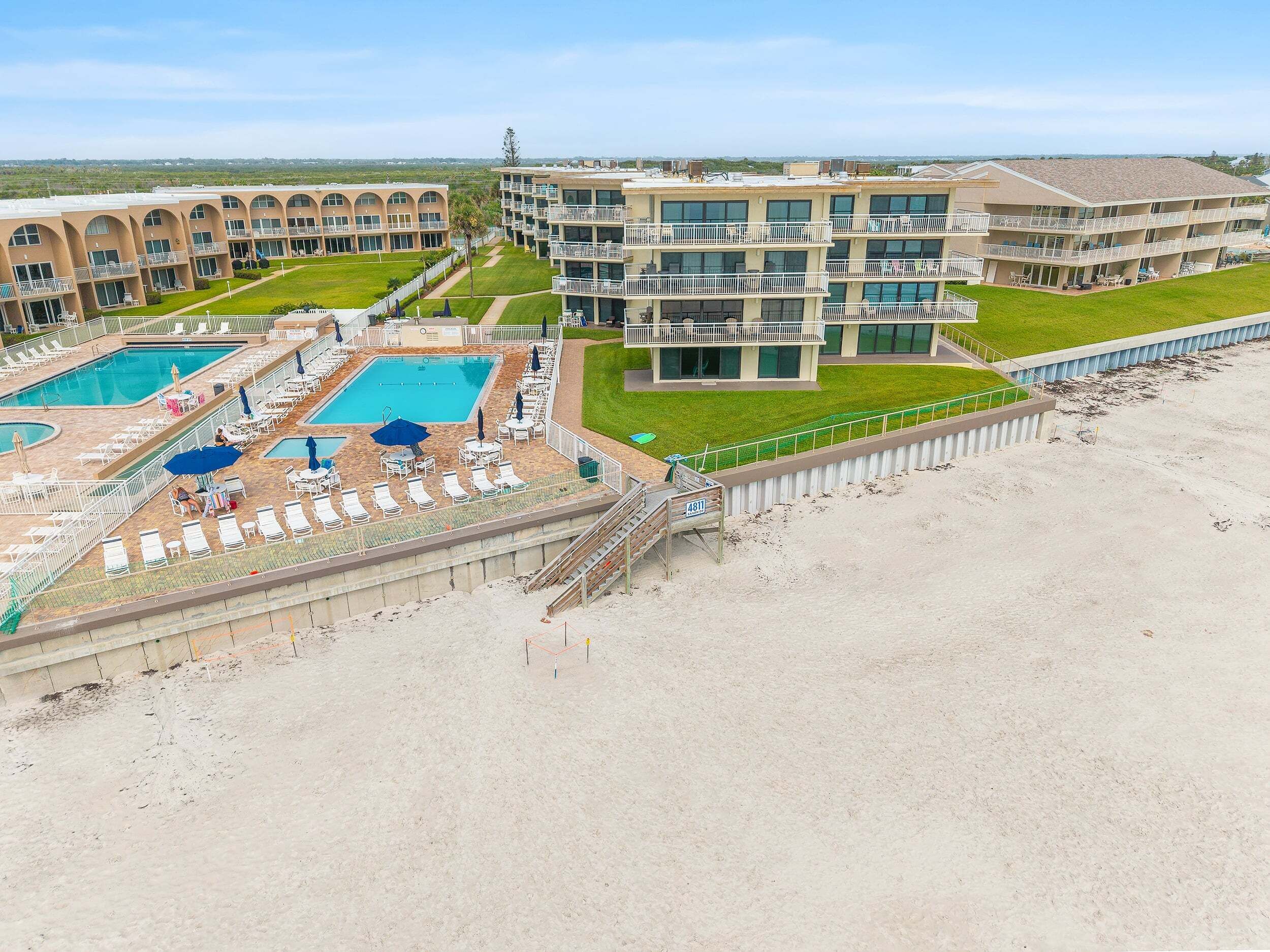 A hotel with multiple swimming pools, a beach area, and a view of the ocean.