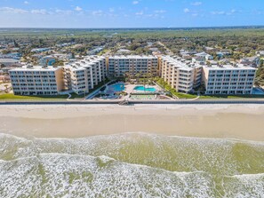 Un hôtel en bord de mer composé de plusieurs bâtiments, doté d’une piscine et donnant sur la plage.