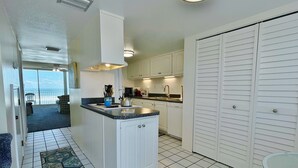 Una cocina con armarios blancos, encimera de granito y vistas al exterior.