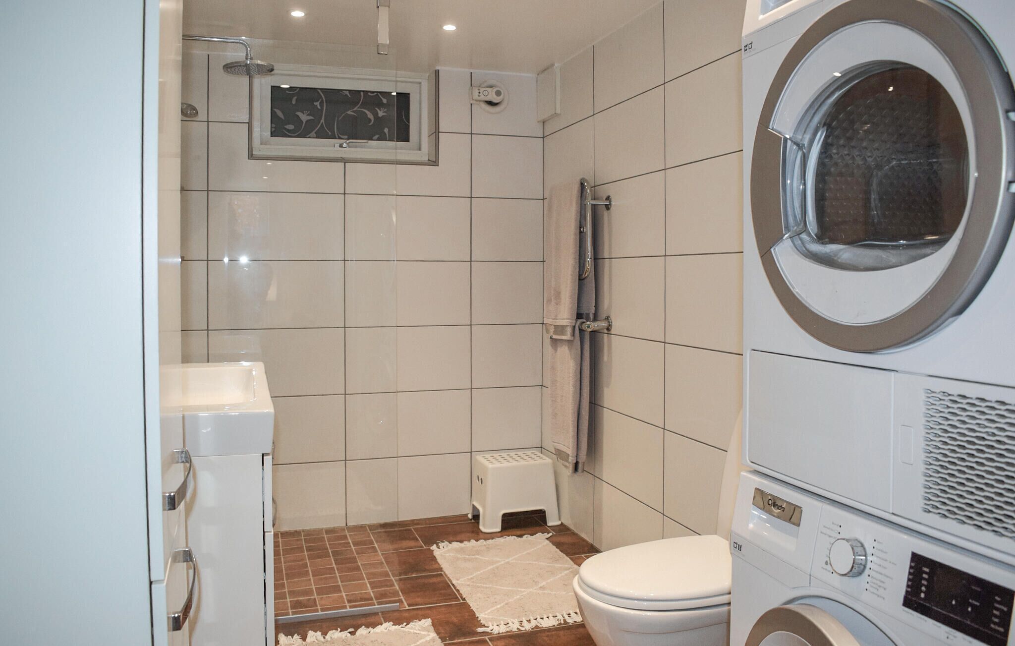 A compact bathroom with a shower, toilet, and washing machine.