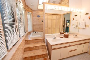 A bathroom with wooden stairs, a bathtub, a large mirror with lights, and wooden cabinets. - Soundside-Resort Amenities, Comm Pool-322, Out of Bounds (Corolla)