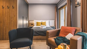 A modern hotel room with a bed, a chair, a sofa, and a small table with fruits. - Calma Wanna Balkon Studio Centrum (Bydgoszcz)