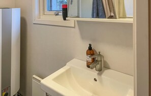 A bathroom with a white sink, a window with a towel, and a bottle of soap. - 1 bedroom lovely apartment in Blidö (Blidö)