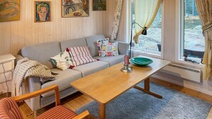 Ein gemütliches Wohnzimmer mit einem grauen Sofa, einem Holztisch und einem gestreiften Sessel.