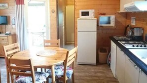 A compact wooden cabin with a dining area, a kitchenette, and a small living space. - Lilie's Chalet, a farm stay (BASSIGNAC)