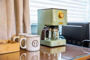 Een koffieapparaat en twee mokken op een tafel.