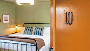 A hotel room with a bed, a nightstand, a lamp, and a door with the number 10.